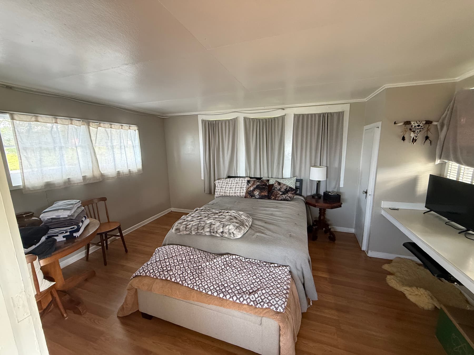 Lodge bedroom with a made-up queen bed, layered blankets, bedside lamp, and warm wood floors