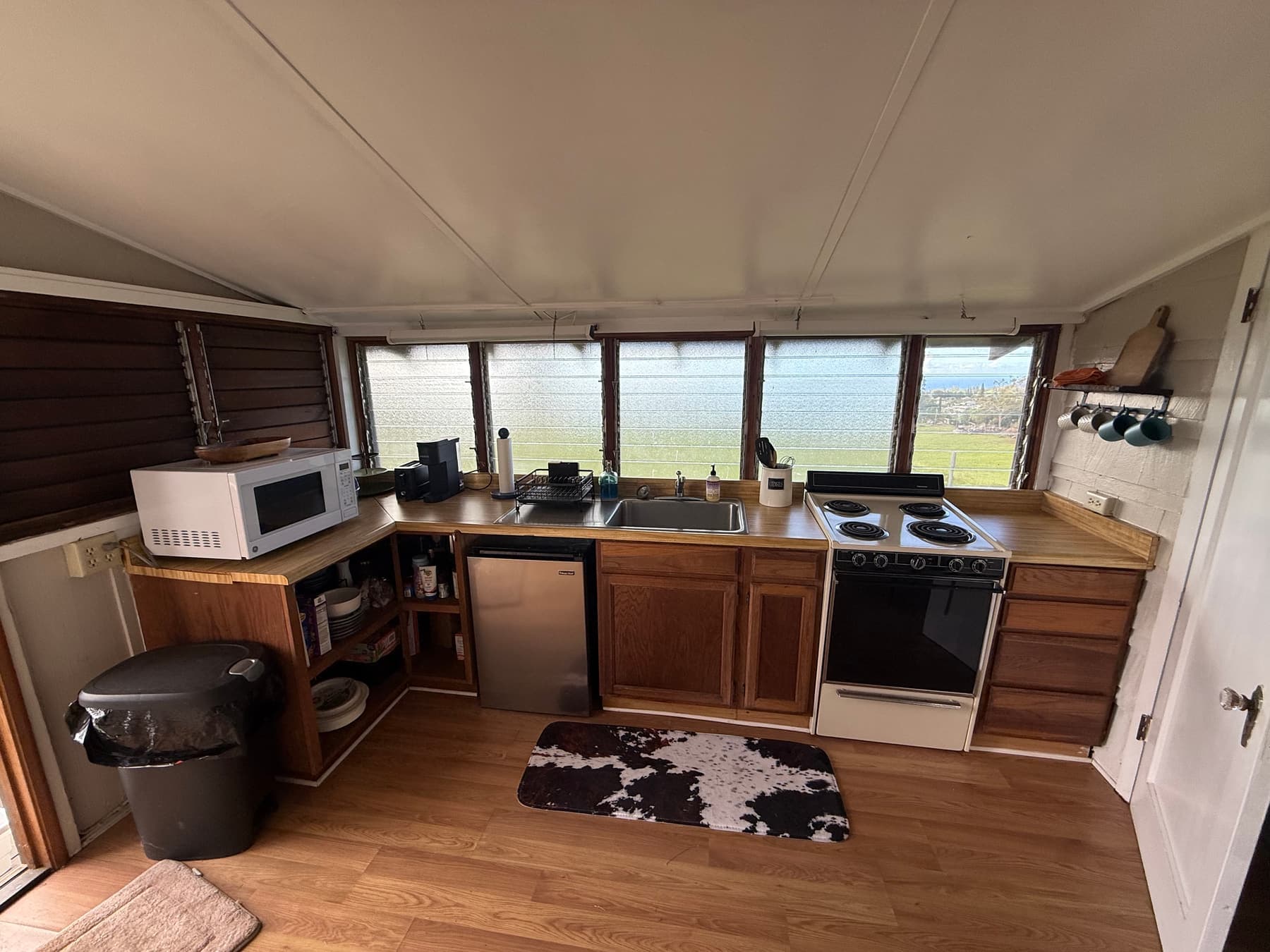 Lodge kitchen with a full range, refrigerator, and microwave, with windows looking over green pasture to the ocean